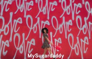 girl in front of wall with "love" written several times all over it