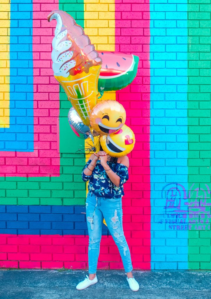 girl holding laughing emoji balloons on april fools' day