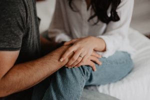 woman holding man's hand over her knee