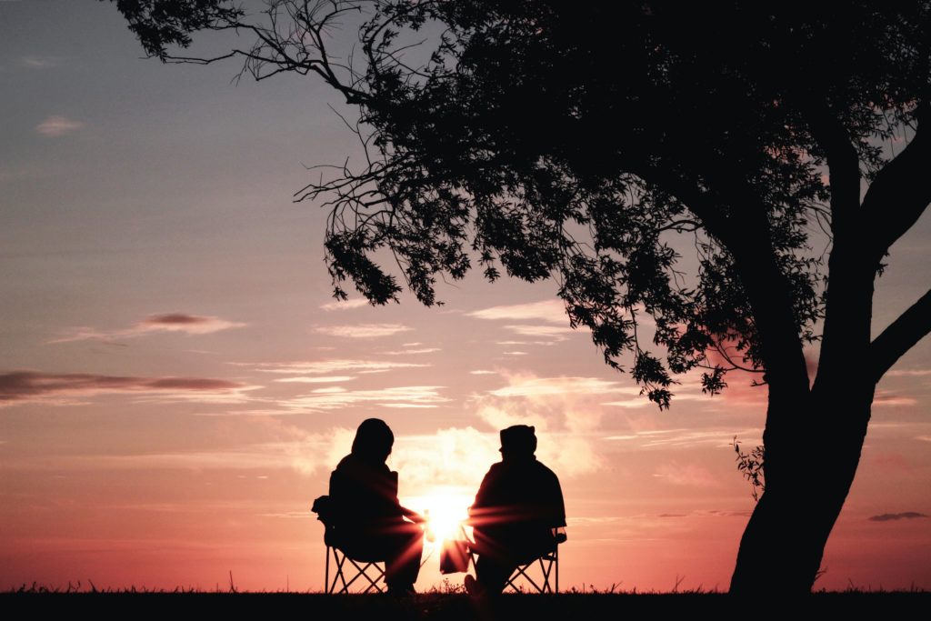 woman sitting with distant man under a tree