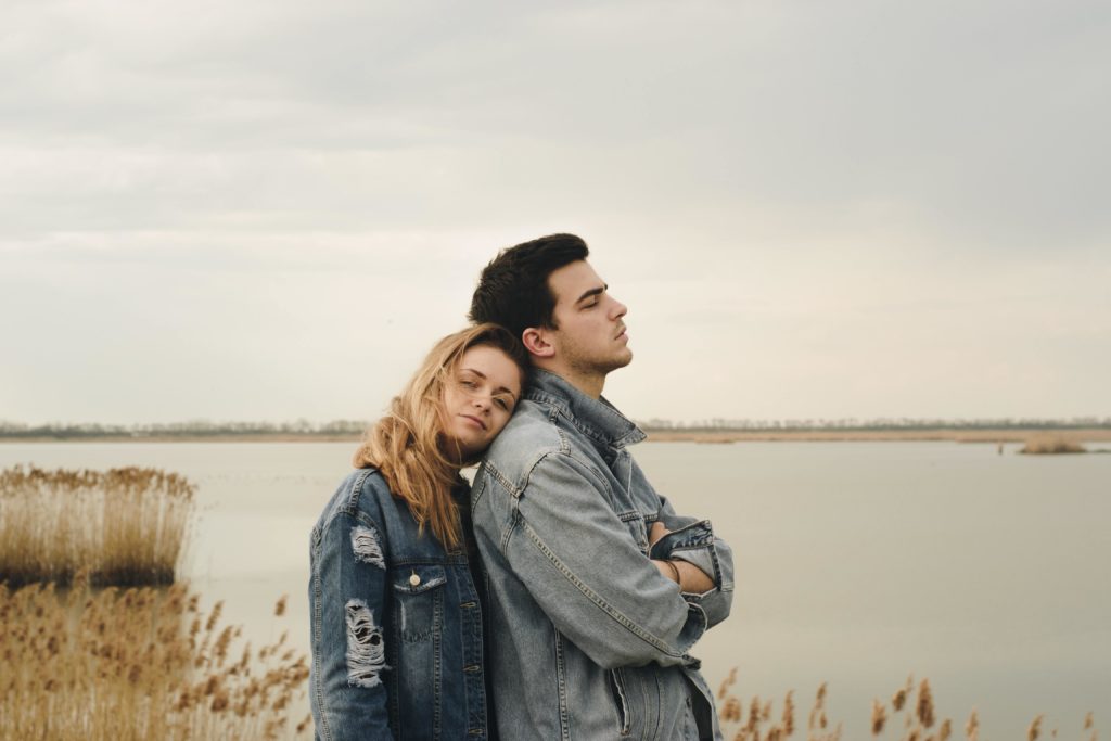 woman leaning her head on the shoulder of her distant boyfriend