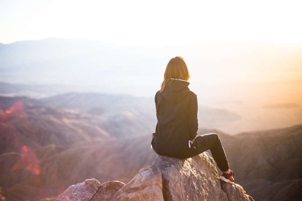 self-confident girl reflecting on top of mountain