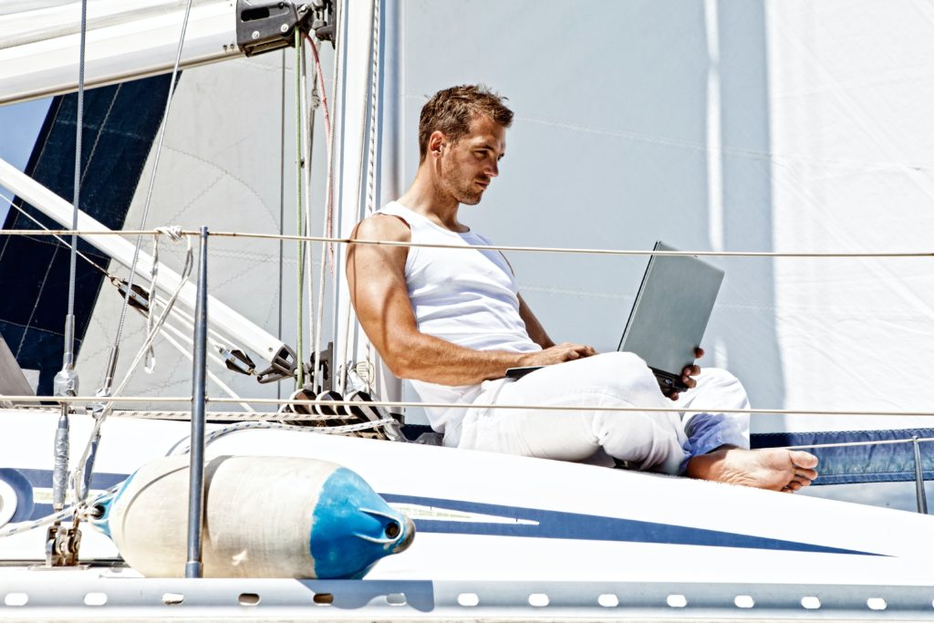 man using his laptop on a boat, example of a good picture for a sugar daddy profile