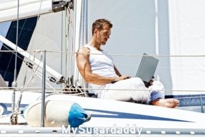 man using his laptop on a boat, example of a good picture for a sugar daddy profile