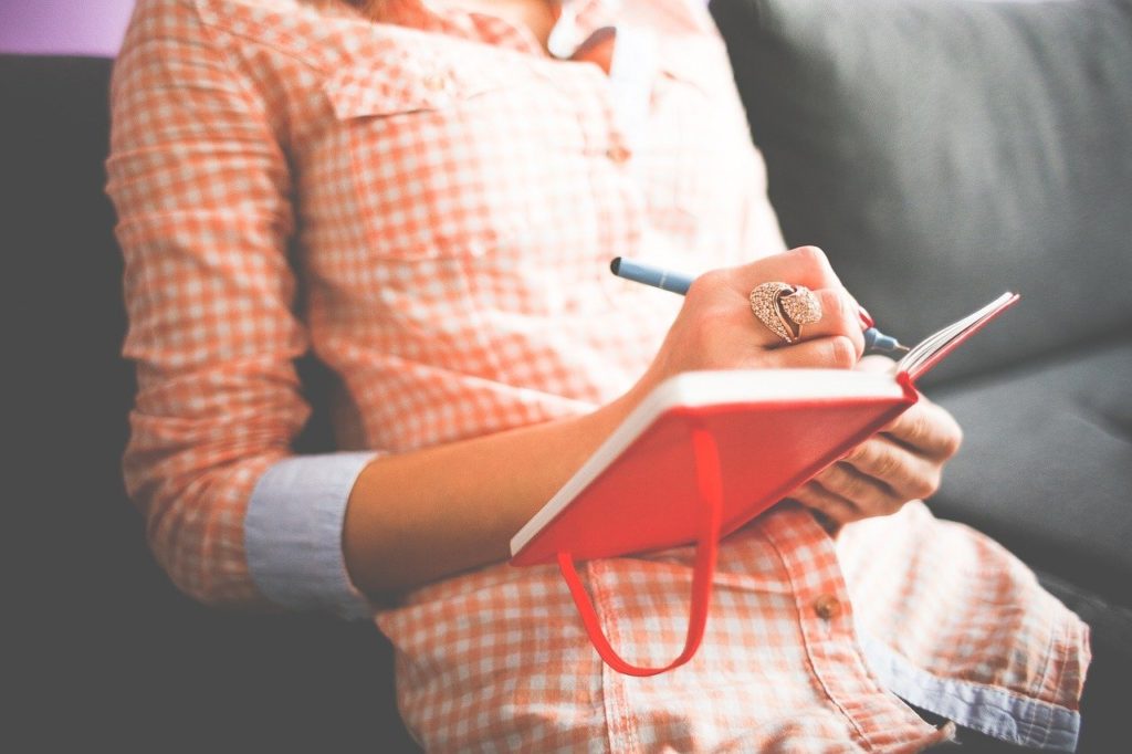 woman writing in her diary on couch