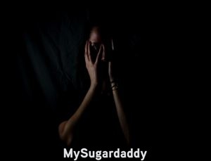 woman with her hands to her face in the dark suffering because of the current self-improvement trend