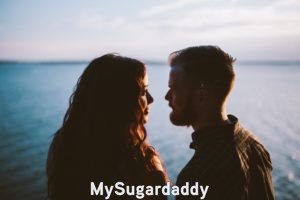 sugar baby looking into the eyes of the sugar daddy of her dreams in front of lake