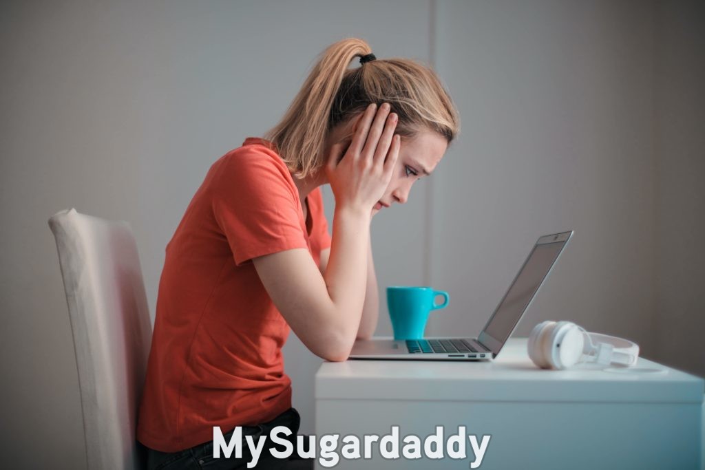 sugar daddy scam making girl feel bad hunched over her laptop