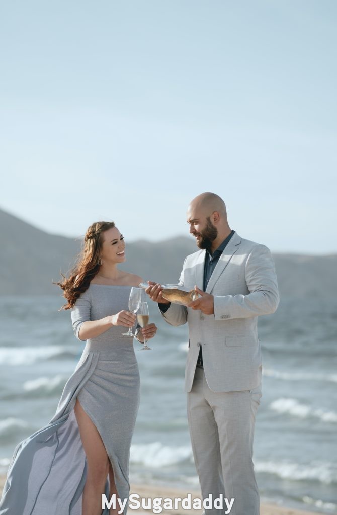 whale daddy with sugar baby having champagne at beach